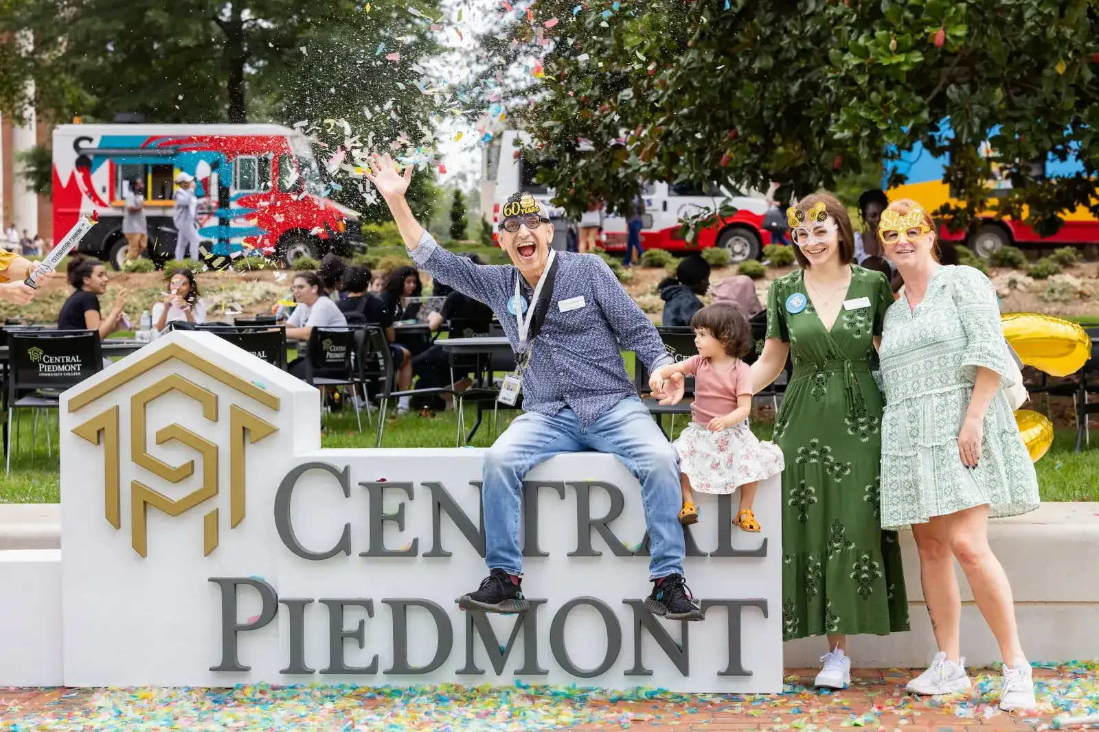 A family posing at the Central Piedmont monument sign during a community event
