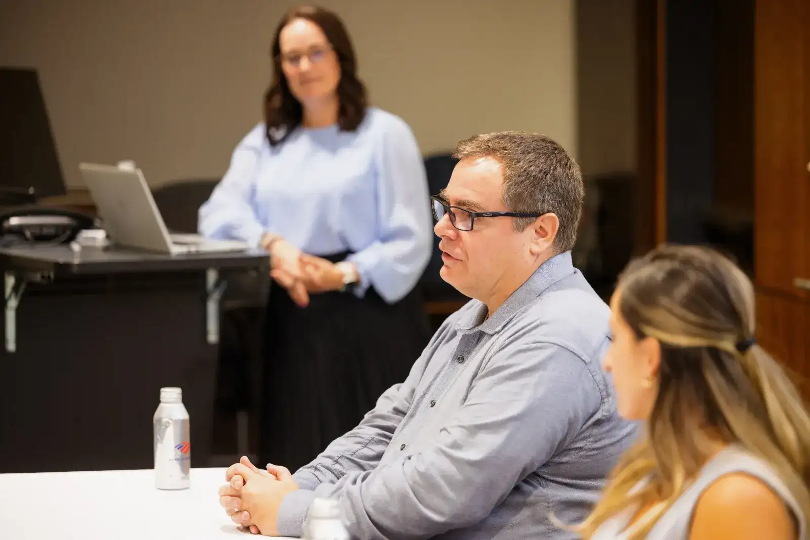 Instructor presenting to a small group of students seated around a meeting table