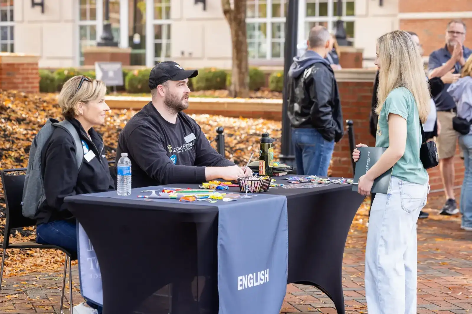 Staff at an outdoor English placement table talking with students