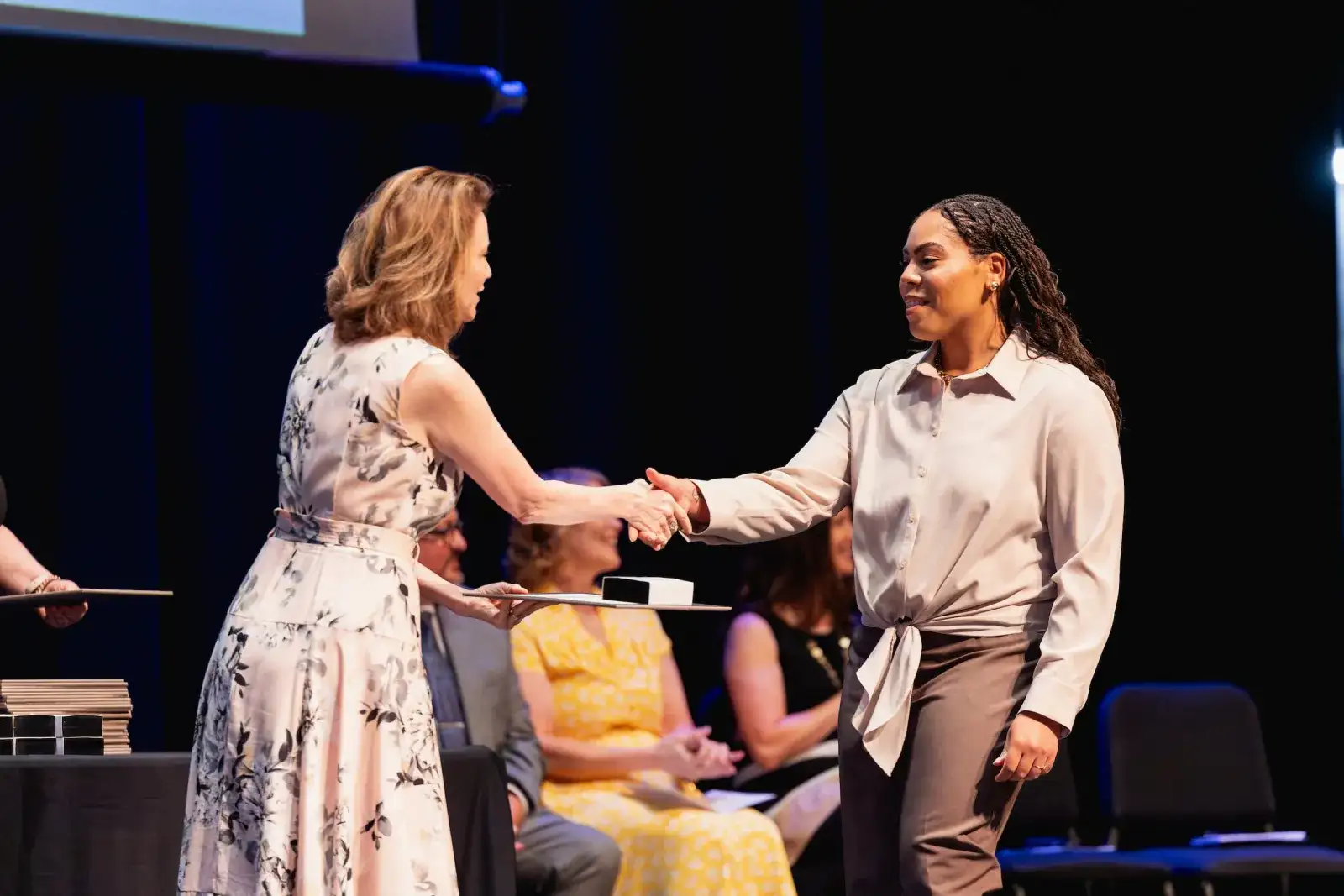 Scholarship recipient shaking hands with a presenter on stage at an award ceremony