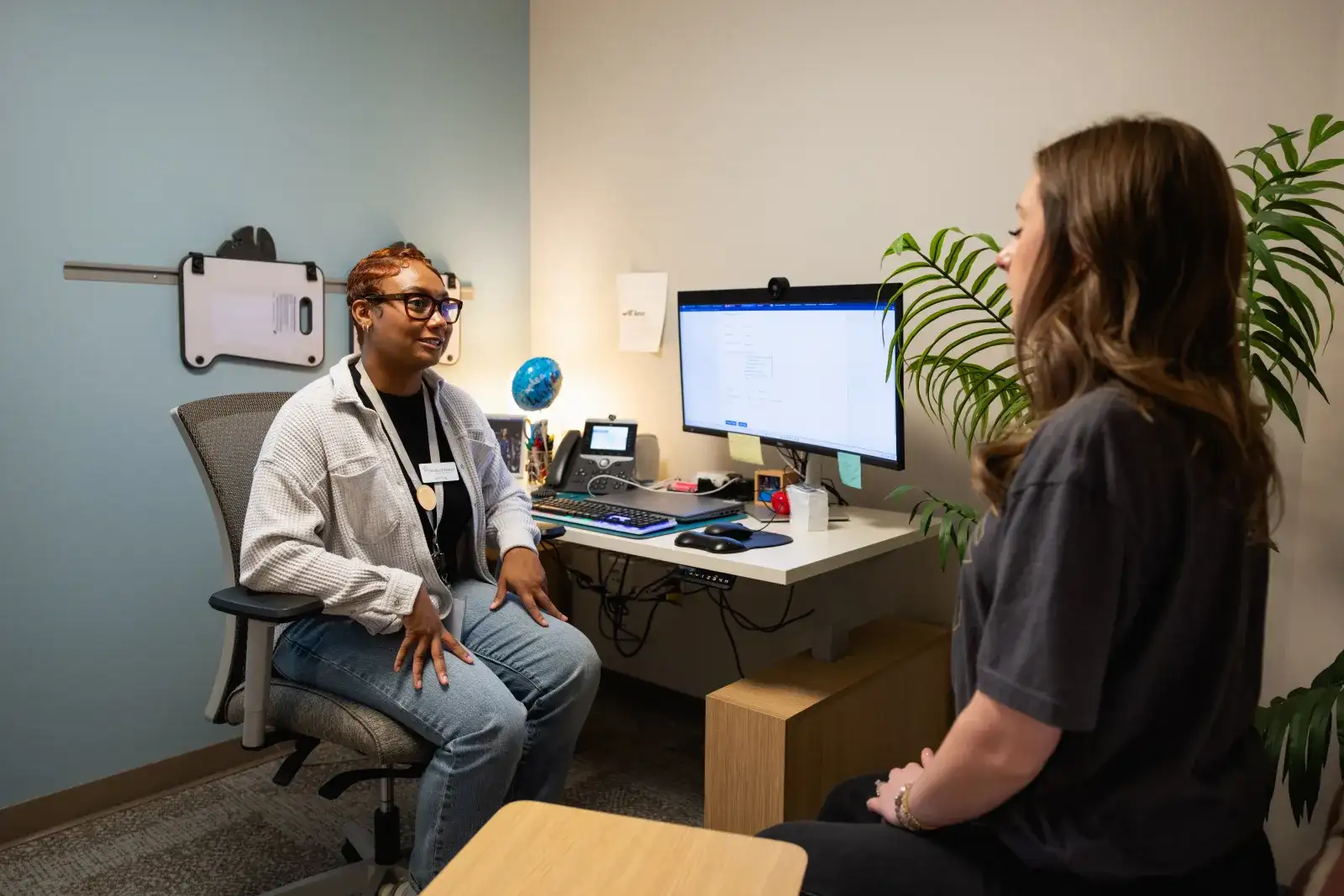 Health services staff member talking with a student in a campus clinic room