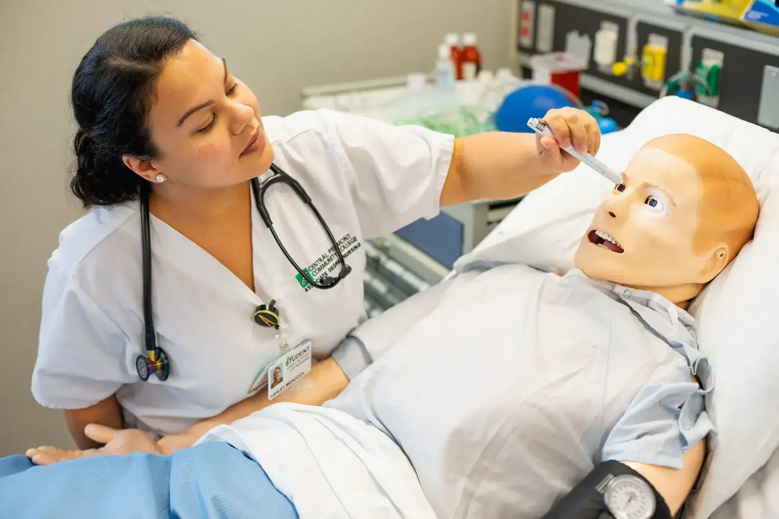 Nursing student caring for a patient simulator in a hospital bed