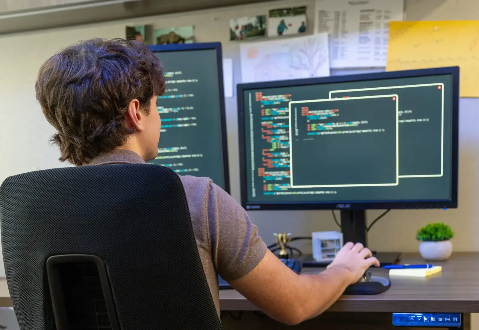 Student writing code at a workstation with a large monitor