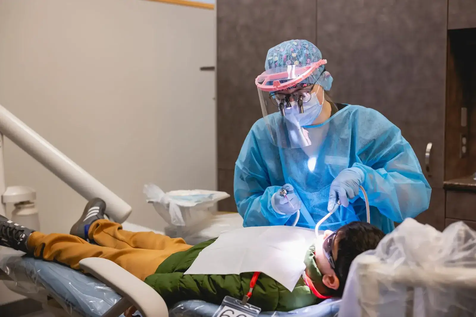Dental student in a face shield treating a patient in the dental clinic