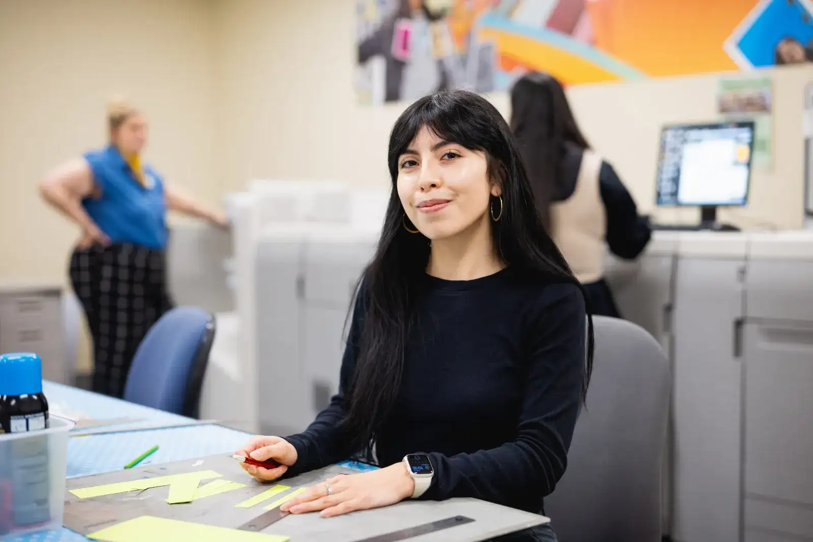 Graphic design student at a workstation in a studio with a colourful mural