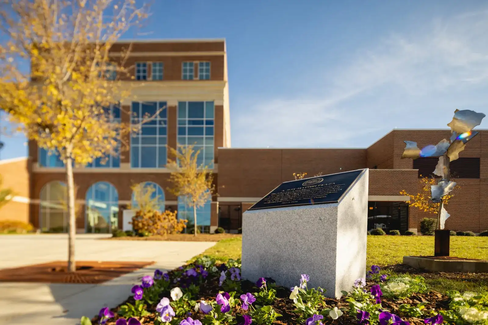 Harper Campus building with a stone sculpture and flower beds in the foreground