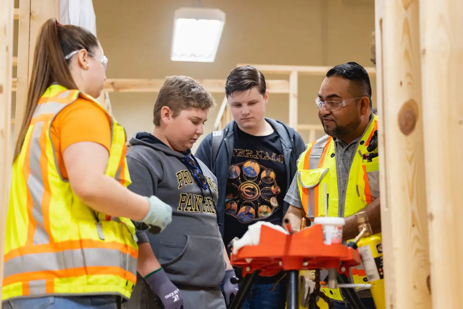 Construction Management students in high-visibility vests working on timber framing
