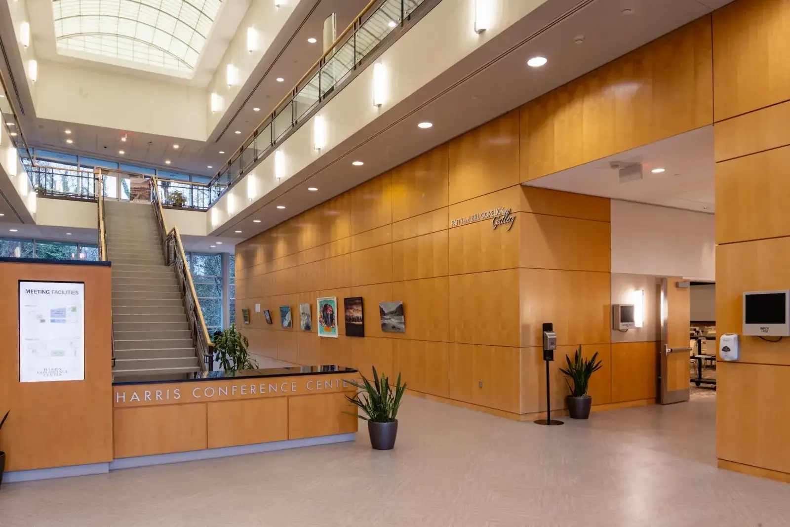 Atrium lobby with a staircase and artwork on wood-panelled walls