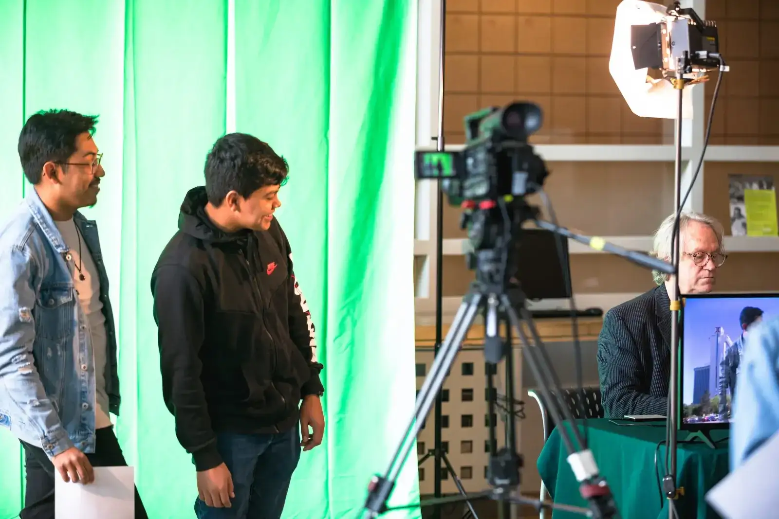 Students filming in front of a green screen with a studio camera and lighting