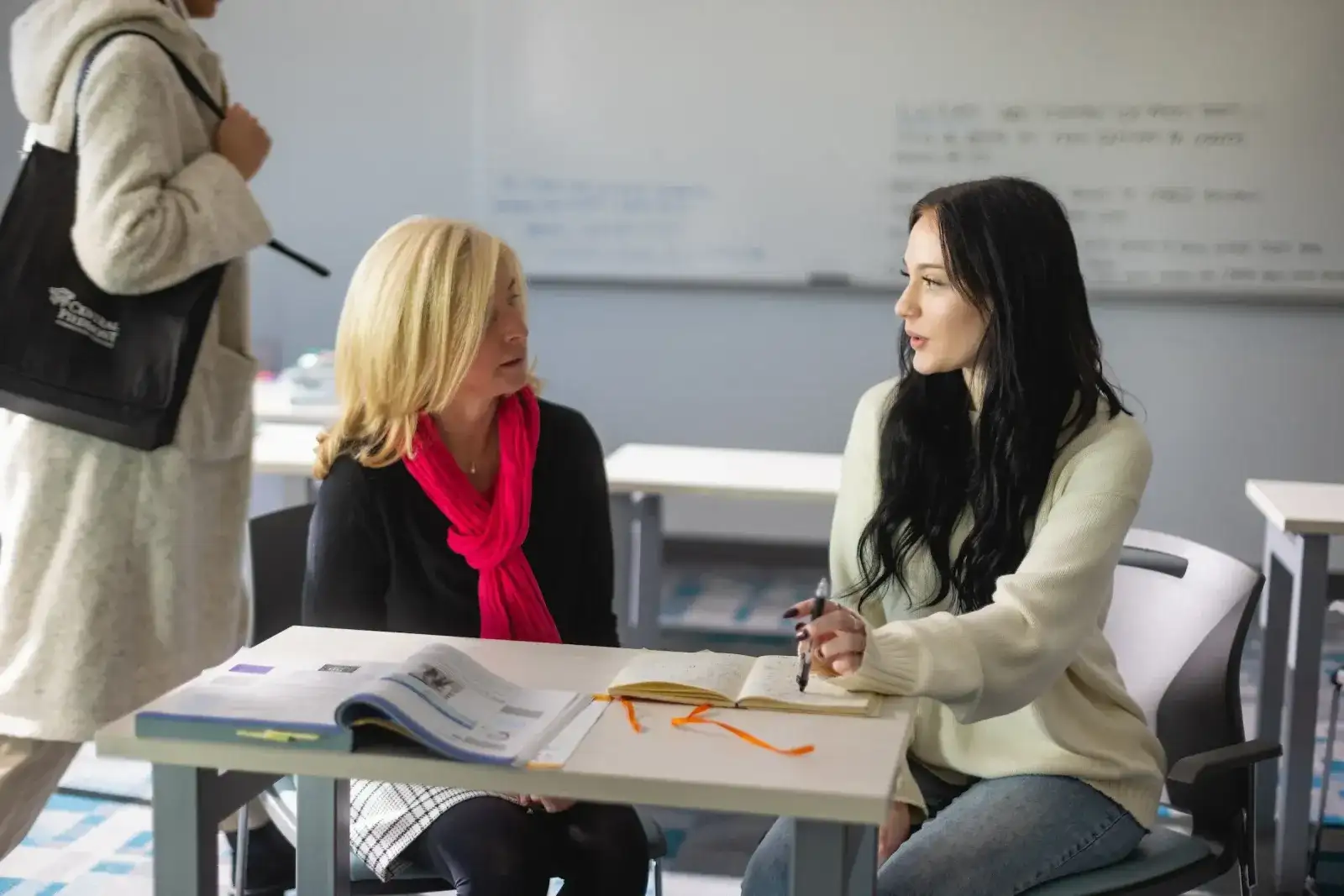 Staff member talking with a student across a desk in a testing centre