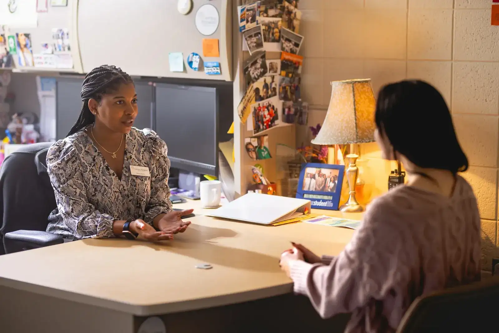 Staff member advising a student across an office desk