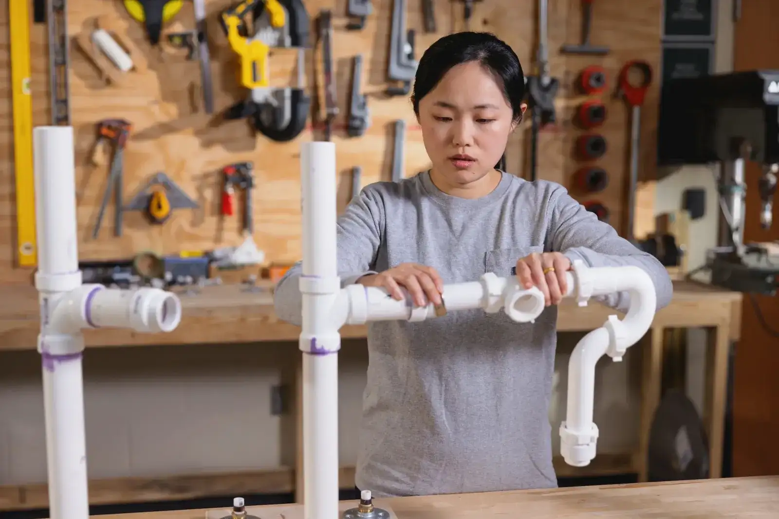 Student assembling PVC pipework at a plumbing workbench