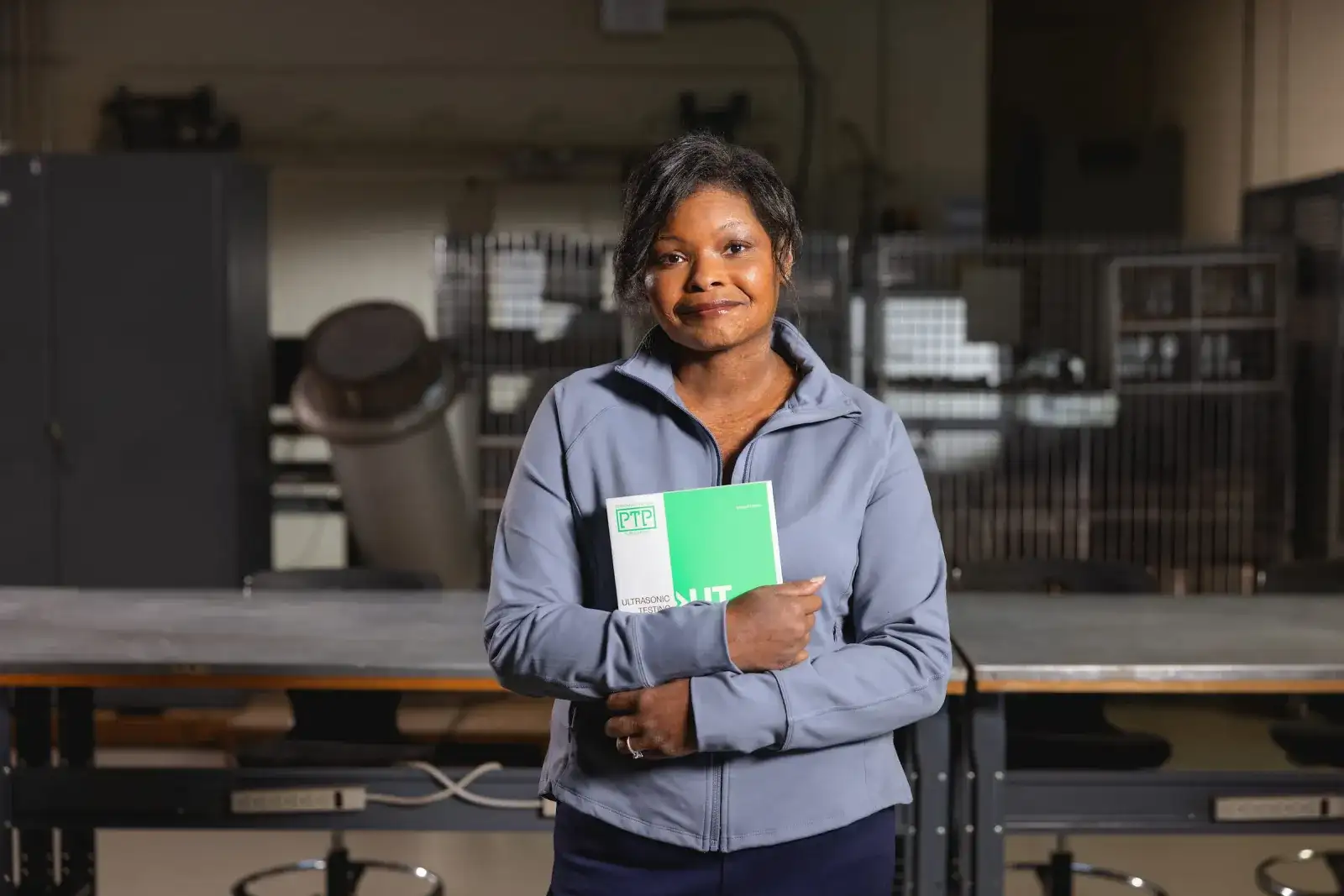 Nondestructive examination technology student holding a manual in a testing workshop