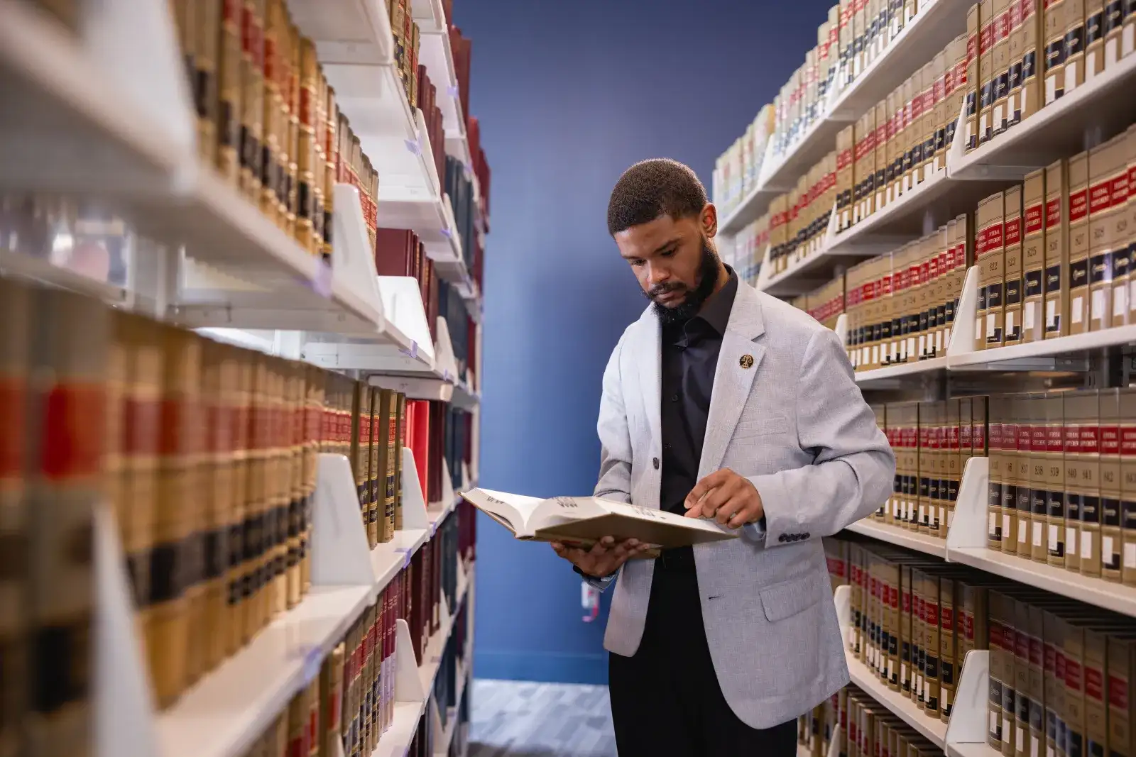 Student in library aisle surrounded by legal books
