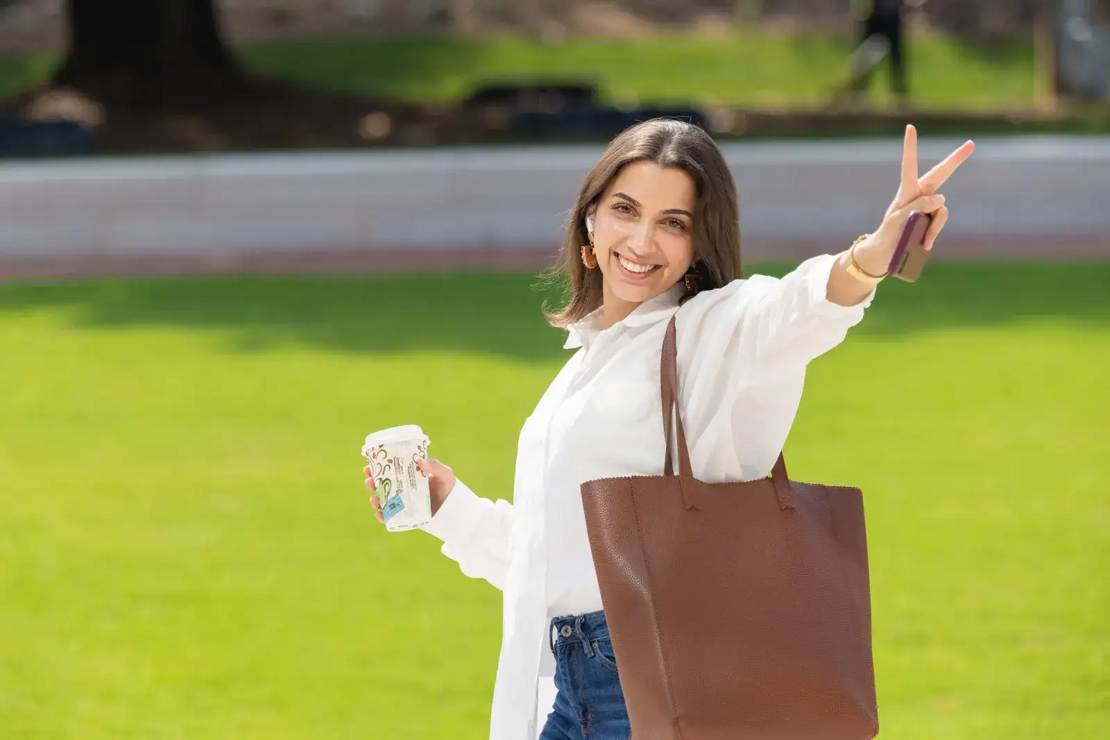 Student with coffee giving peace sign