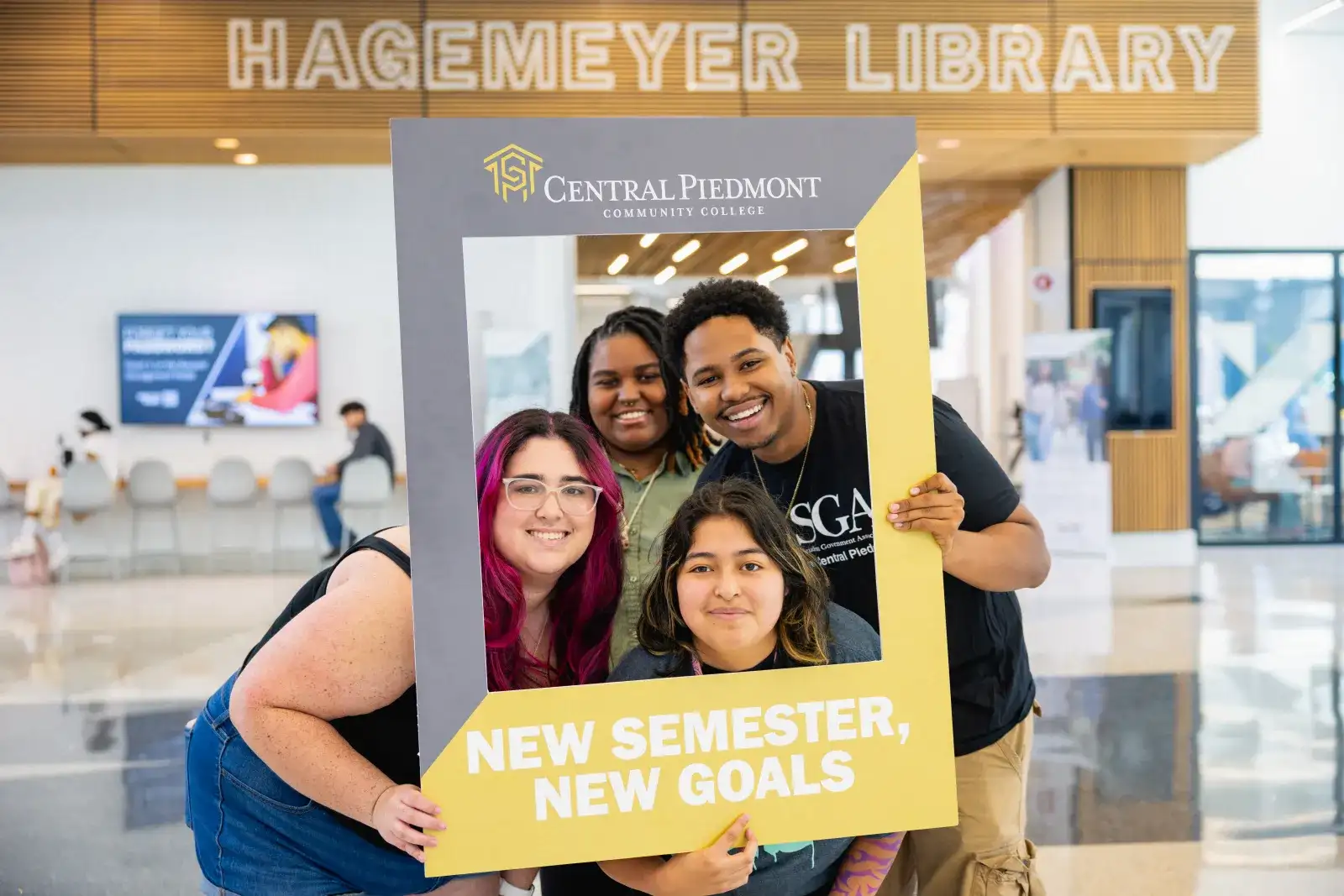 Four students in parr center posing behind oversized picture frame