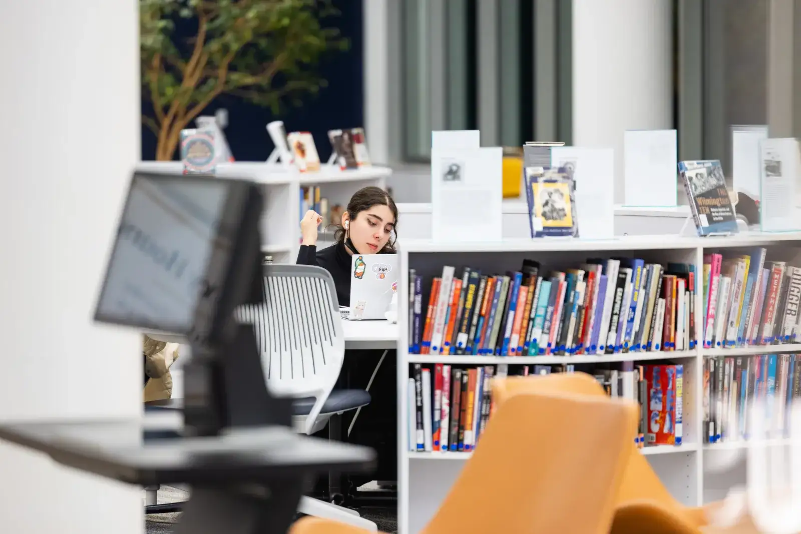 Student in the library behind a stack of books