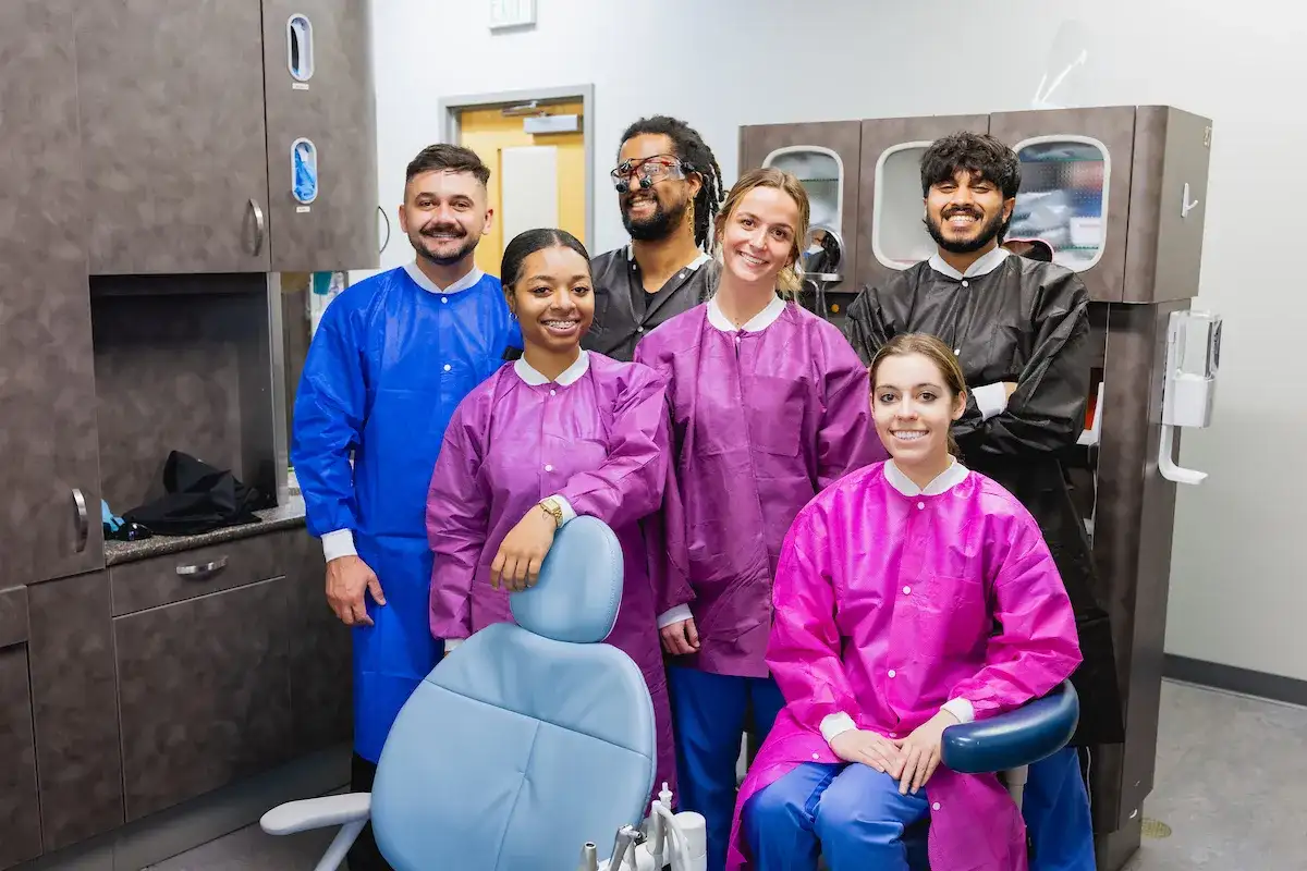 Dental Hygiene program students standing behind a dental chair