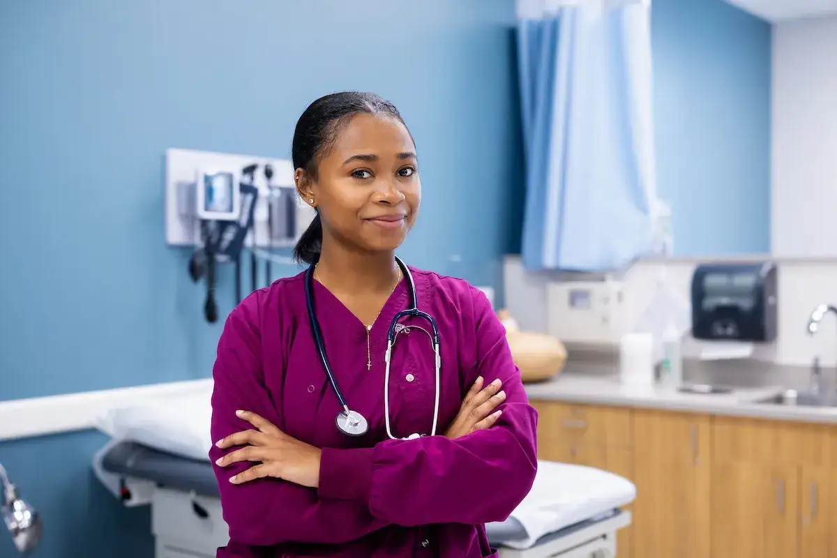 Medical assisting student standing with arms crossed, smiling