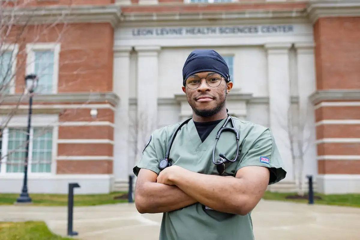 Respiratory Therapy student standing in front of the health sciences building with arms crossed