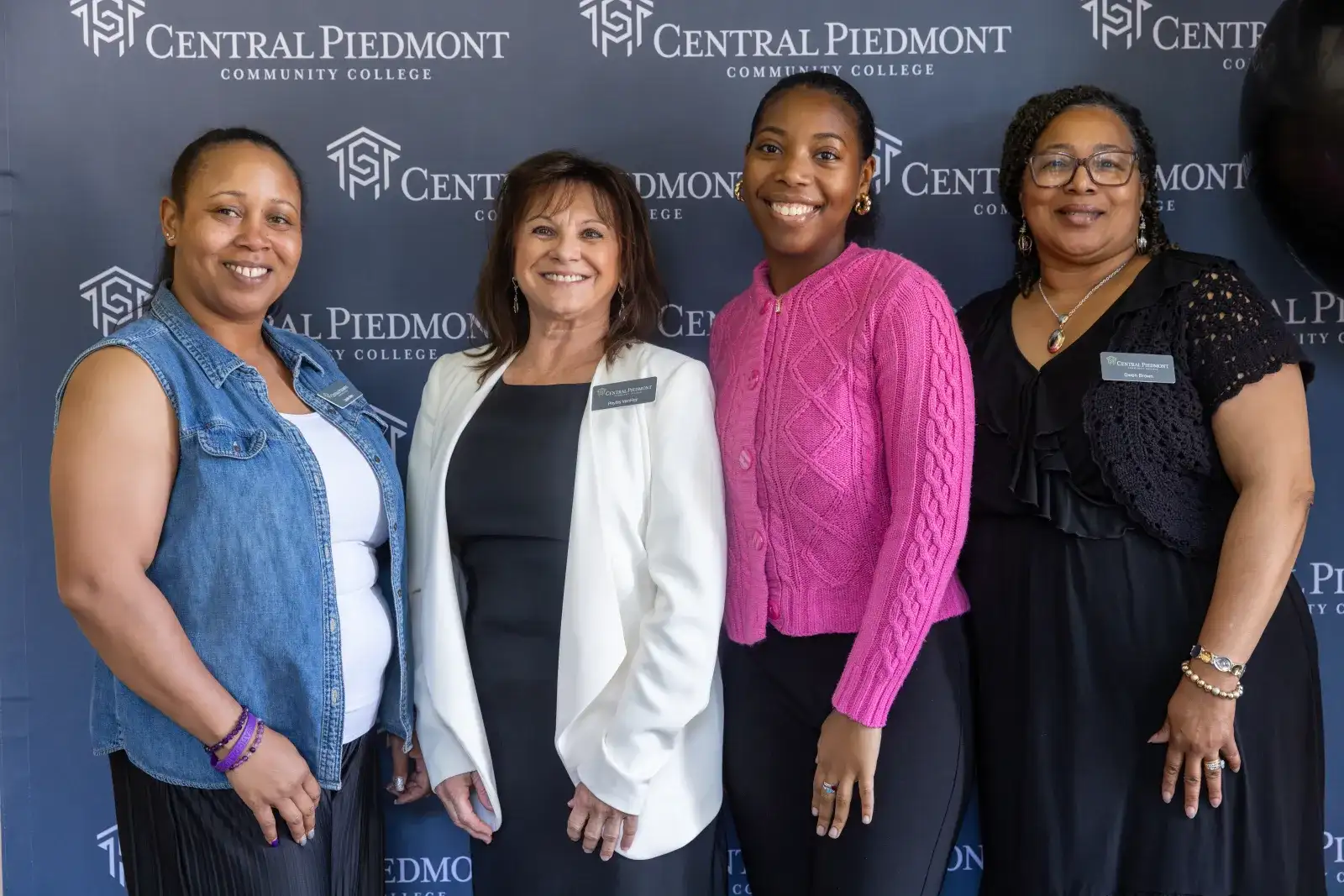 Four women posing in front of a Central Piedmont branded backdrop