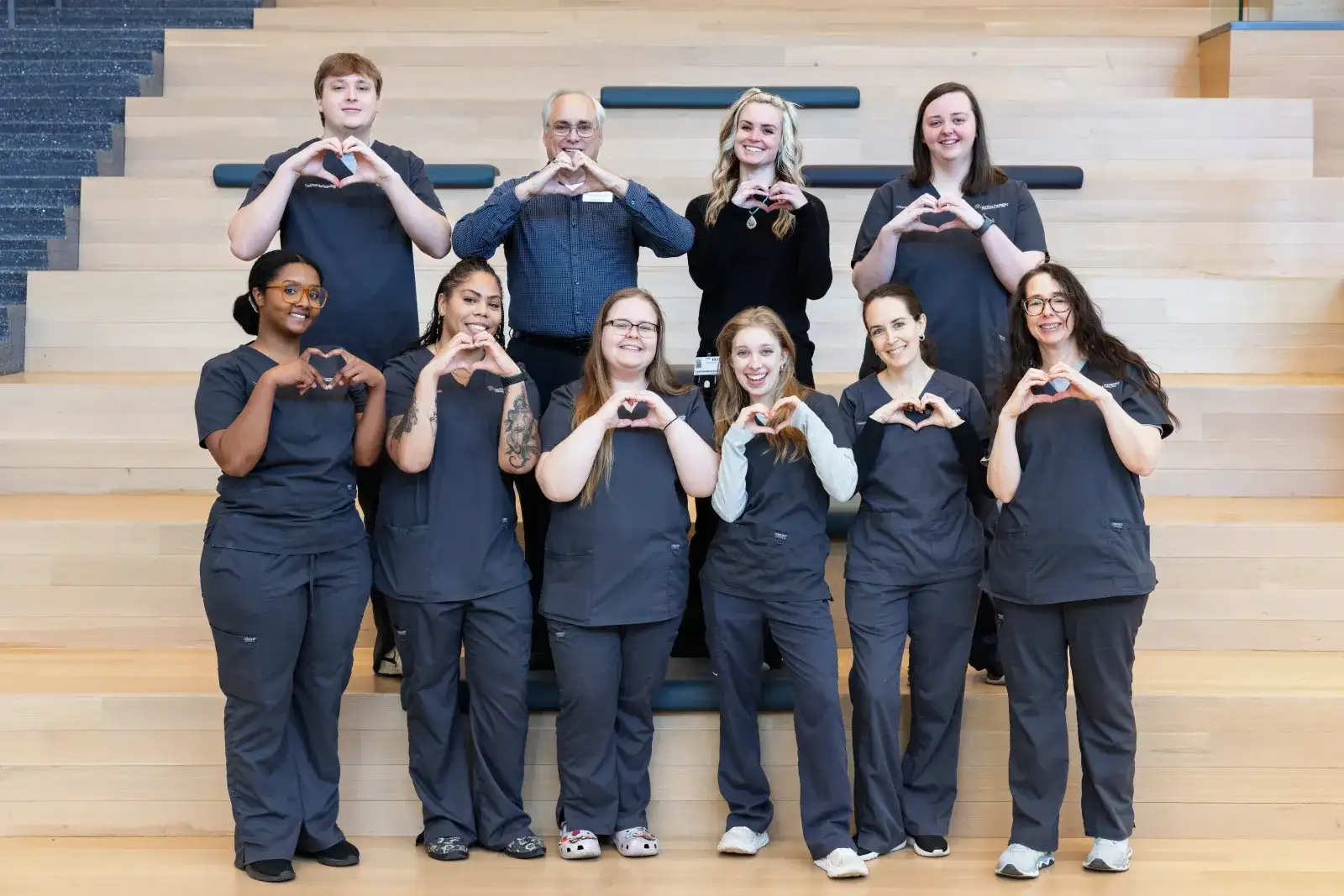 Cardiovascular technology students on stairs at Parr Center making heart shapes with their hands