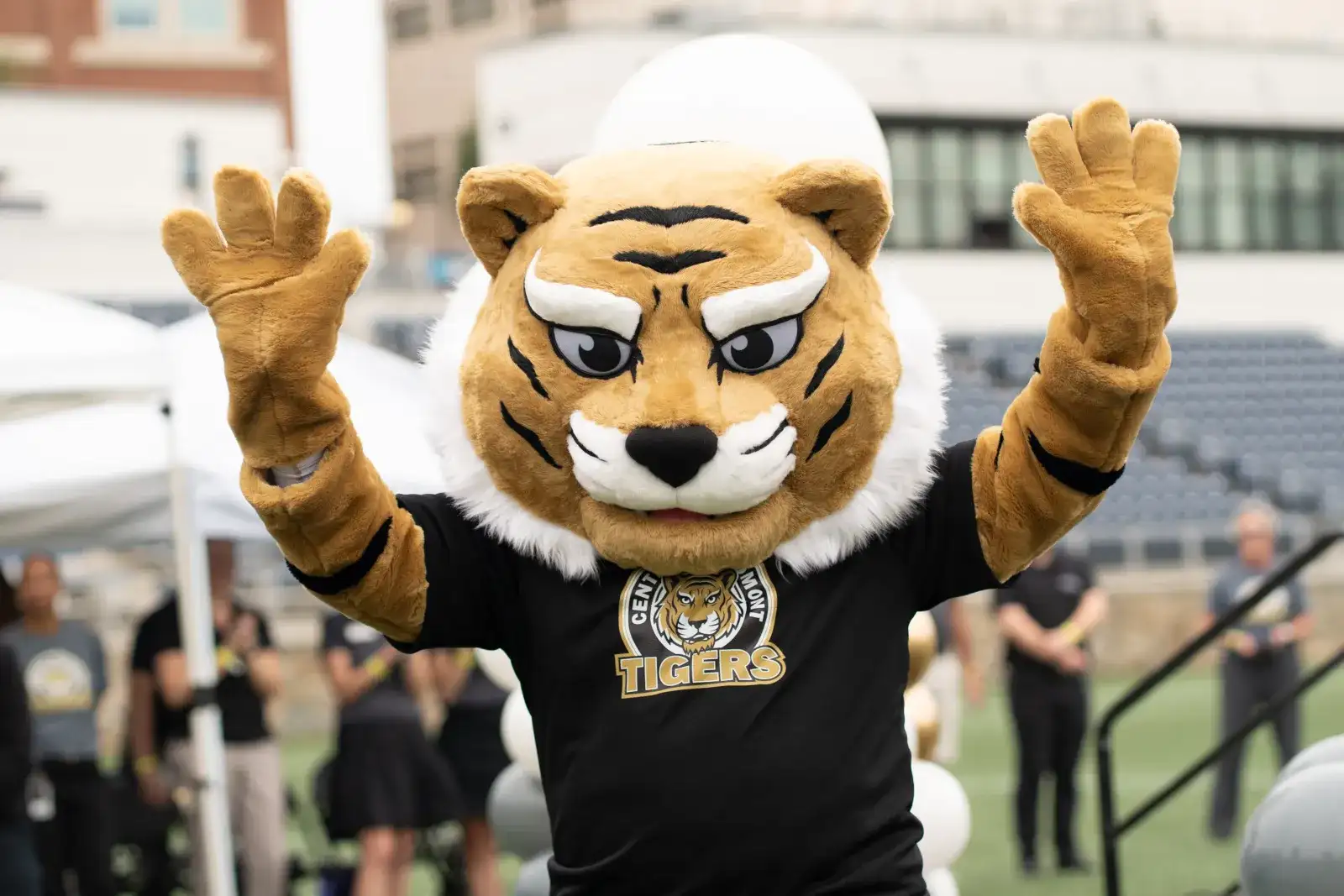 The Central Piedmont tiger mascot named Spark, with hands in the air inside the American Legion Stadium on Central Campus