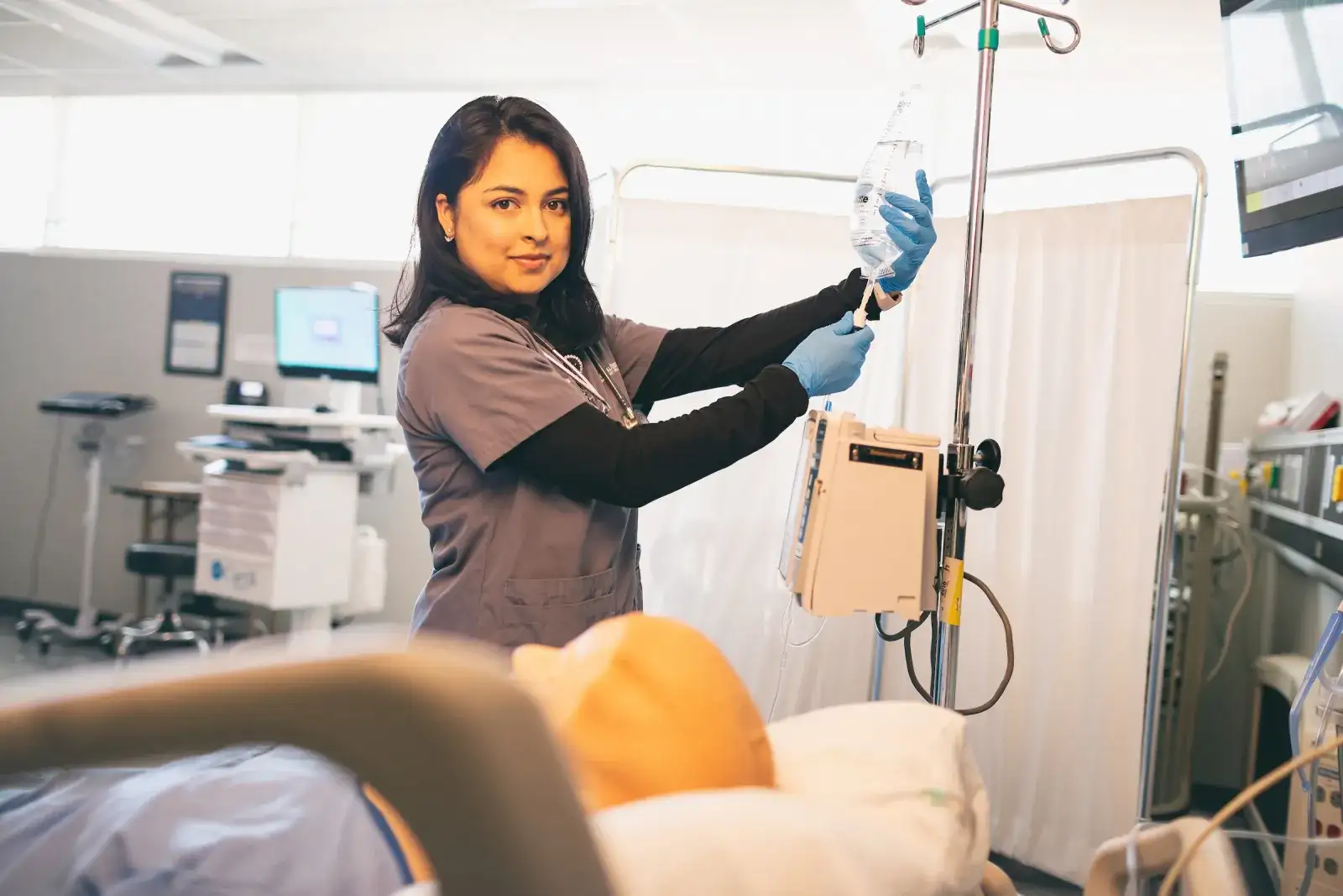 Nursing student hanging a bag of fluids in the healthcare program's simulation center