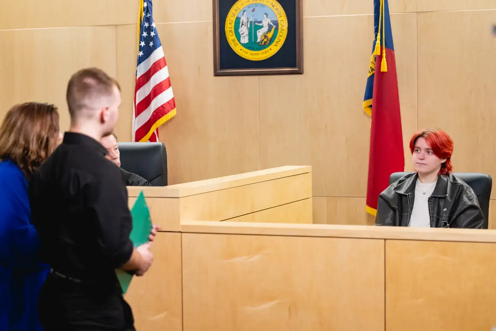 Mock courtroom with a student in the witness box and two students posing as council