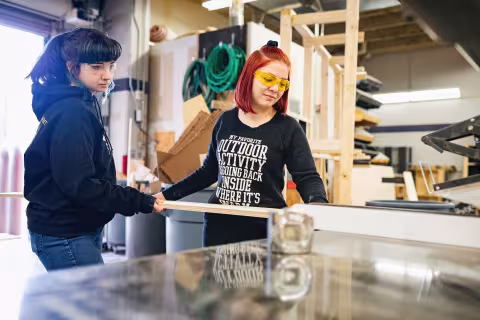 Two students working with timber in a campus workshop