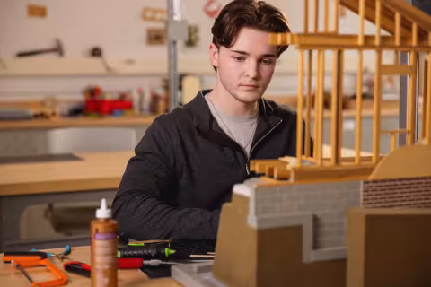 Architectural Technology student assembling a timber scale model of a building