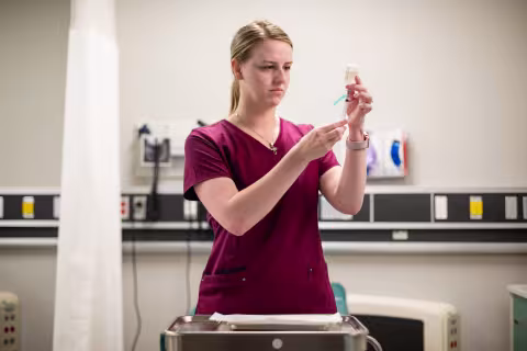 Nursing student preparing a syringe in a clinical skills lab