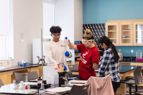 Students in safety goggles conducting an experiment in a science lab