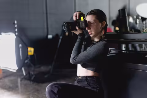 Photography student framing a shot with a DSLR camera in a studio