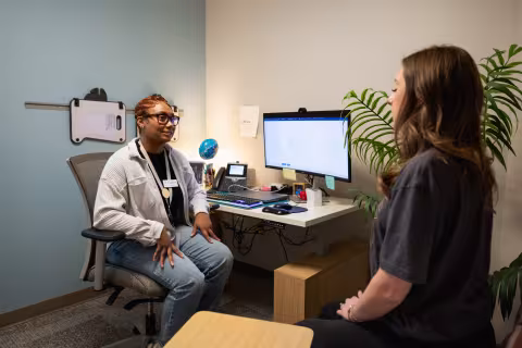 Health services staff member talking with a student in a campus clinic room