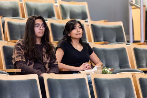 Two students seated together in an auditorium