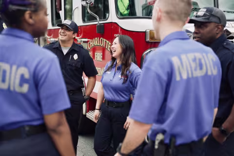 Paramedics and firefighters in uniform standing beside a fire engine