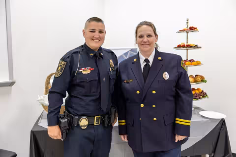 A police officer and a fire officer in dress uniform at a public safety reception