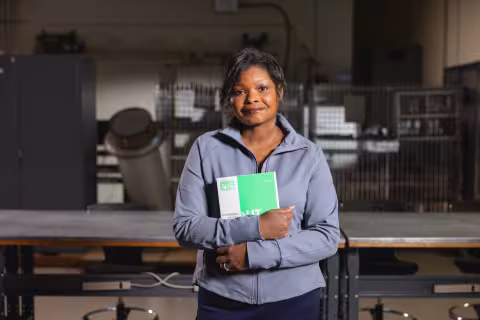 Nondestructive examination technology student holding a manual in a testing workshop