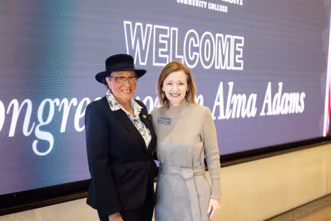 Congresswoman Alma Adams and Kandi Deitemeyer in front of a welcome video wall